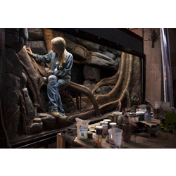 Exhibit Specialist Carolyn Fuchs '96 works to create a habitat for a blue tree monitor lizard at the Bronx Zoo. Photo by Karsten Moran for The New York Times.