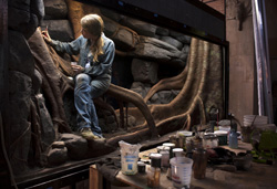 Exhibit Specialist Carolyn Fuchs '96 works to create a habitat for a blue tree monitor lizard at the Bronx Zoo. Photo by Karsten Moran for The New York Times.