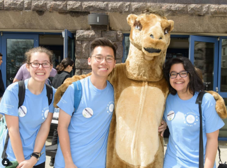 Samirah and two students pose for a photo with the camel mascot