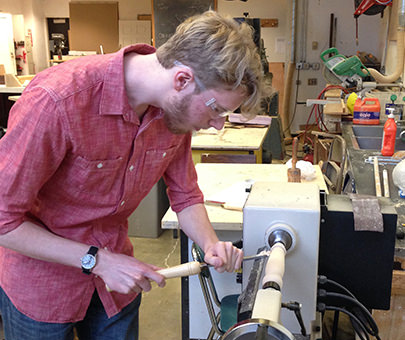 A student uses woodworking equipment in an art studio. 