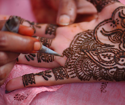 A women applies henna designs to another woman's hands. 