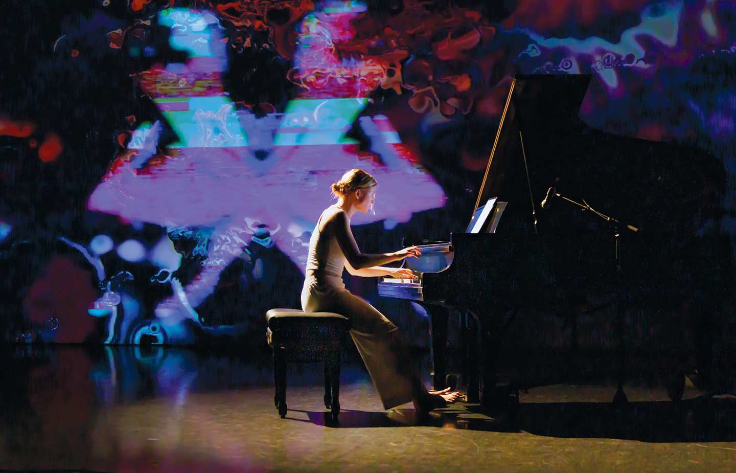 Student playing piano with colored lights in background
