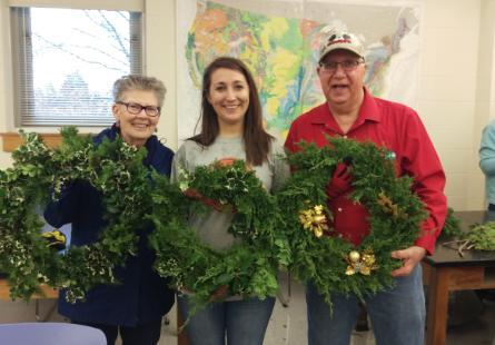 Three participants in the wreath making workshop show off their wreaths