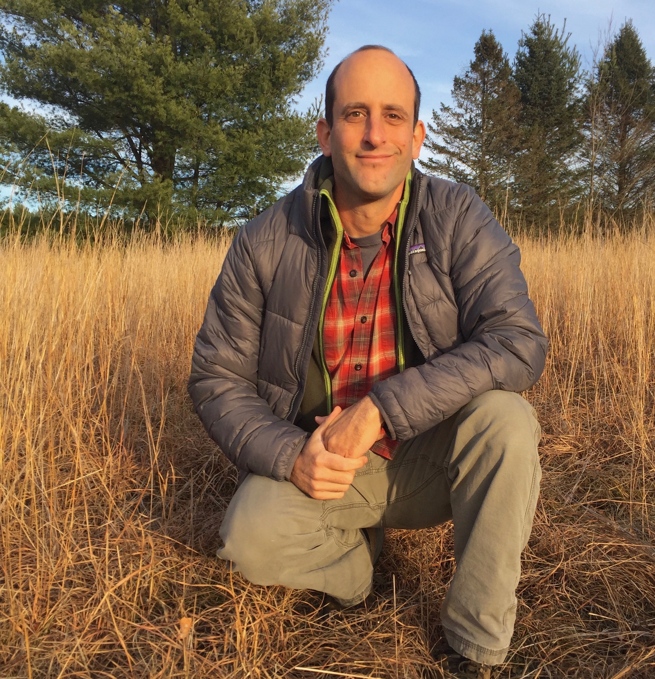 Owen Wormser kneeling in a meadow