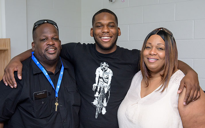 A young man poses with his parents. 
