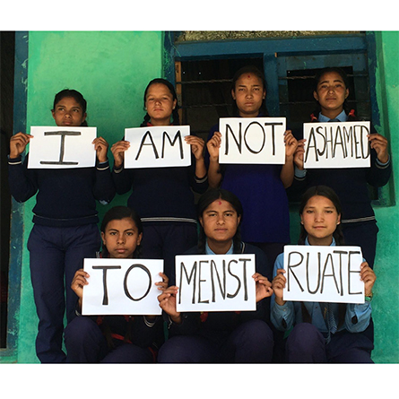 Teenage girls from rural Nepal hold signs that read, 