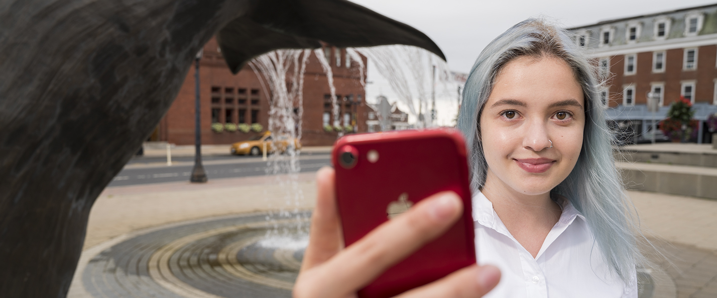 Lera Shynkarova ’20 poses with her cell phone in downtown New London