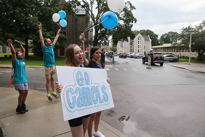 Students cheer as new students arrive on campus. 