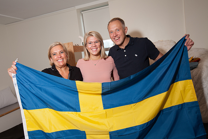 A new student and her parents pose with the Swedish flag. 