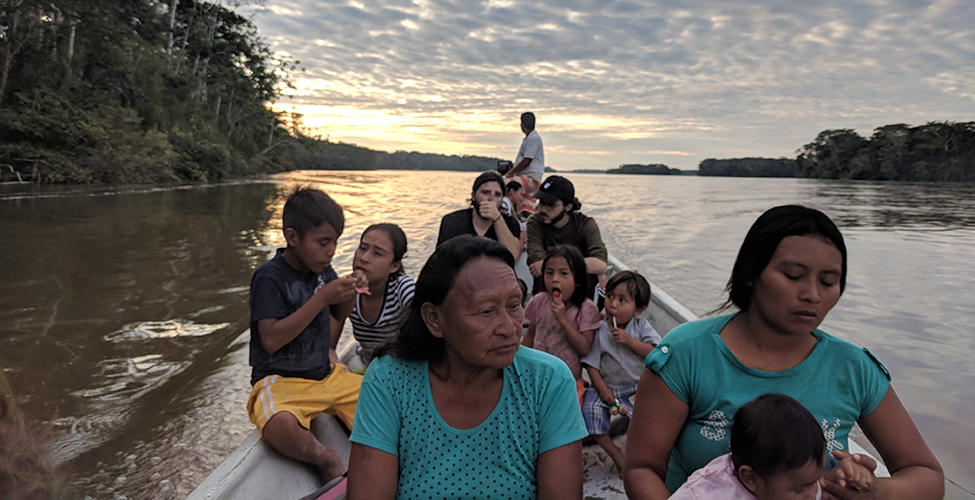 Members of the Secoya Indigenous travel down a river in the Amazon rainforest