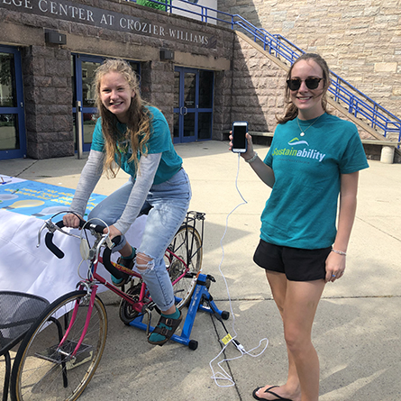 Sustainability Fellow Julia Graham '22 (left) and Senior Sustainability Fellow for Communications and Engagement Ashlyn Healey '20 demo a bike-powered charging station on the first day of Campus Sustainability Week.