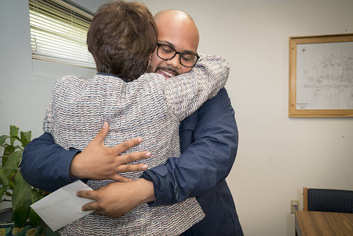 Angelo Urena hugs President Katherine Bergeron after she surprises him with the Service Excellence Award. 