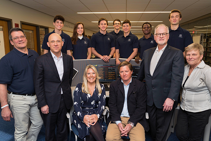 Garrett; CEO of Oxford Lane Capital Corp. and Board of Trustees Vice Chair Jonathan Cohen ’87; Lori Langdon P’22; Ryan Langdon P’22; Folts, and Banker pose with finance students (back row) with the new Bloomberg Terminal. 
