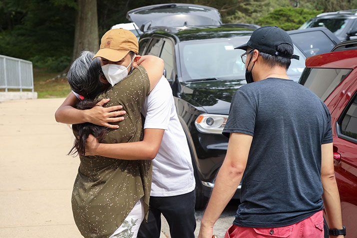 A student hugs his family member goodbye