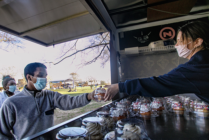 A student takes a cupcake from the NoRA cupcake truck.