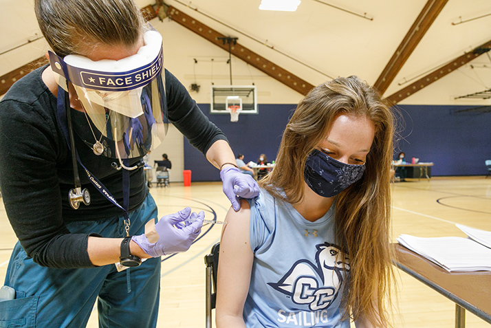 A nurse gives a student a COVID-19 vaccine. 