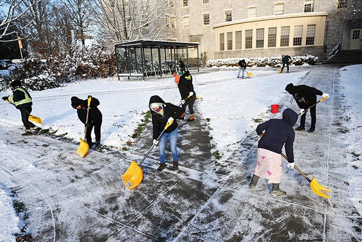 People work to clear the first snow of the season from campus walkways.