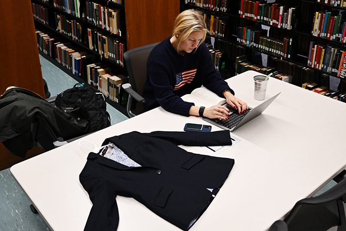 A student studies with a clothing design piece on a table.