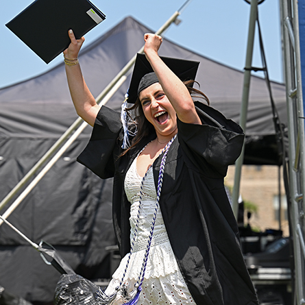 A graduate celebrates after walking across the stage.