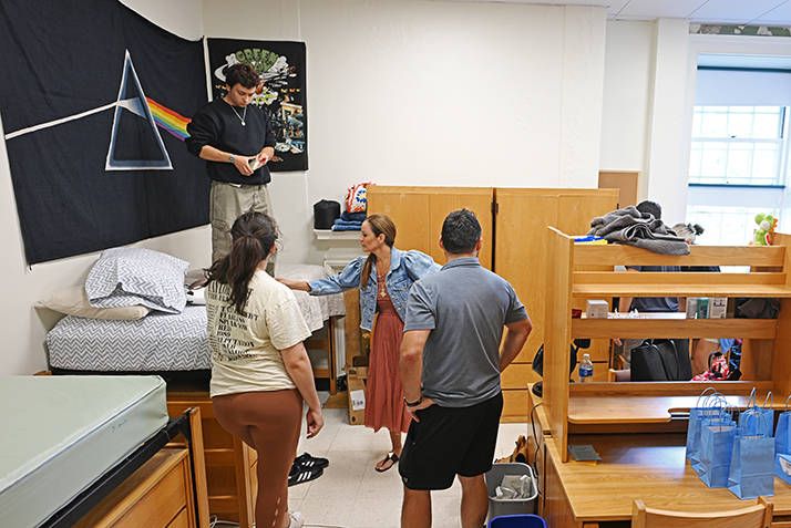 A new students sets up a dorm room with the help of family.
