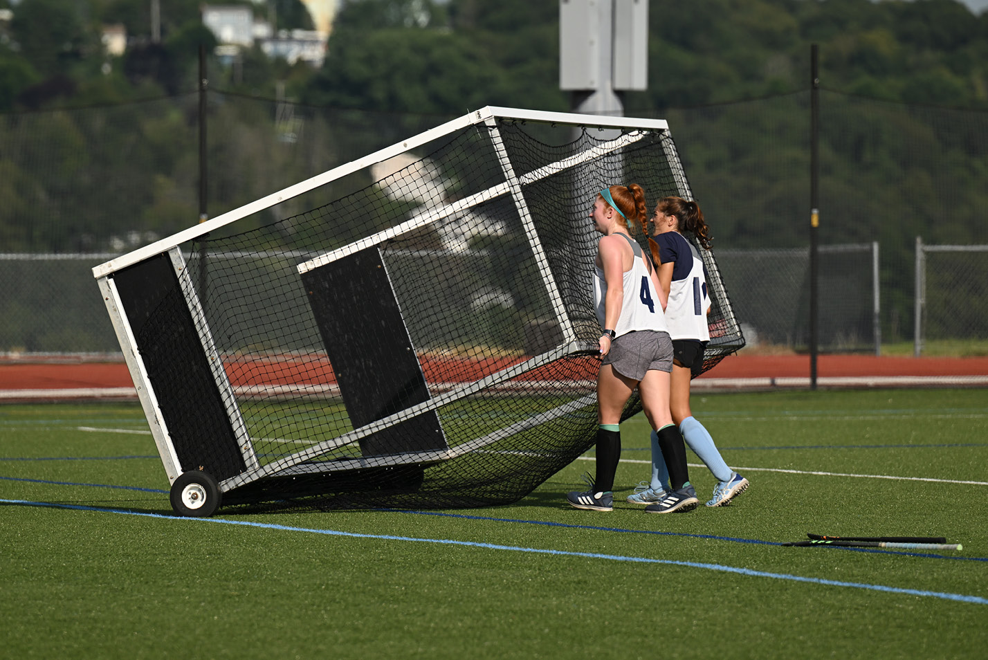 Field hockey players push a goal onto the field before practice.