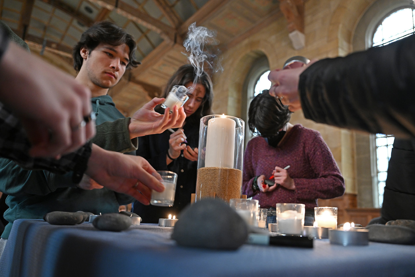 Students step forward to light candles and write their burdens on stones at an ecumenical Ash Wednesday service at Harkness Chapel.