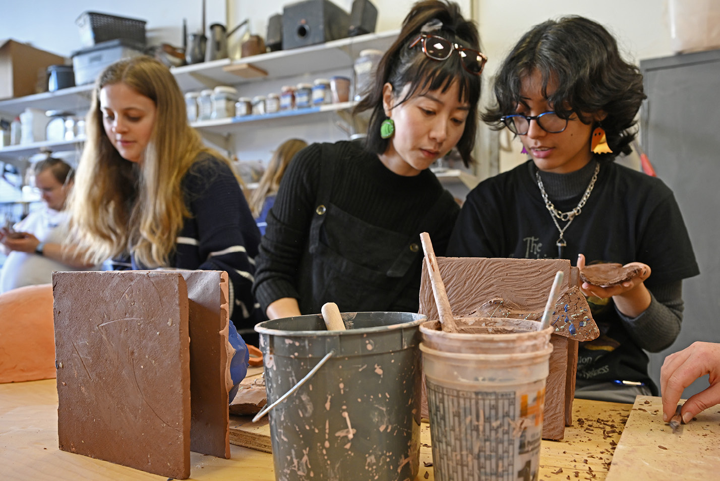 Chenlu Hou works on ceramics with students in ART 232 Clay in Context.