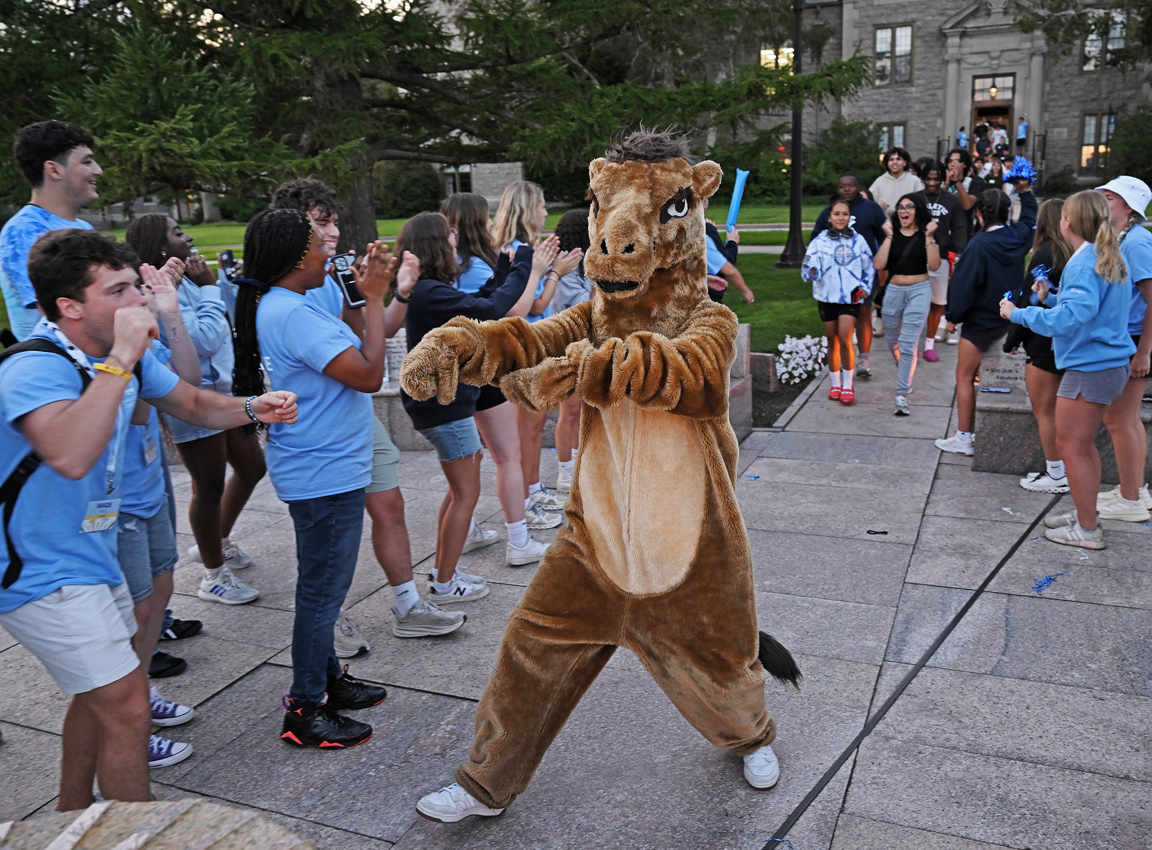 A person in a camel costume celebrates with a crowd of college students