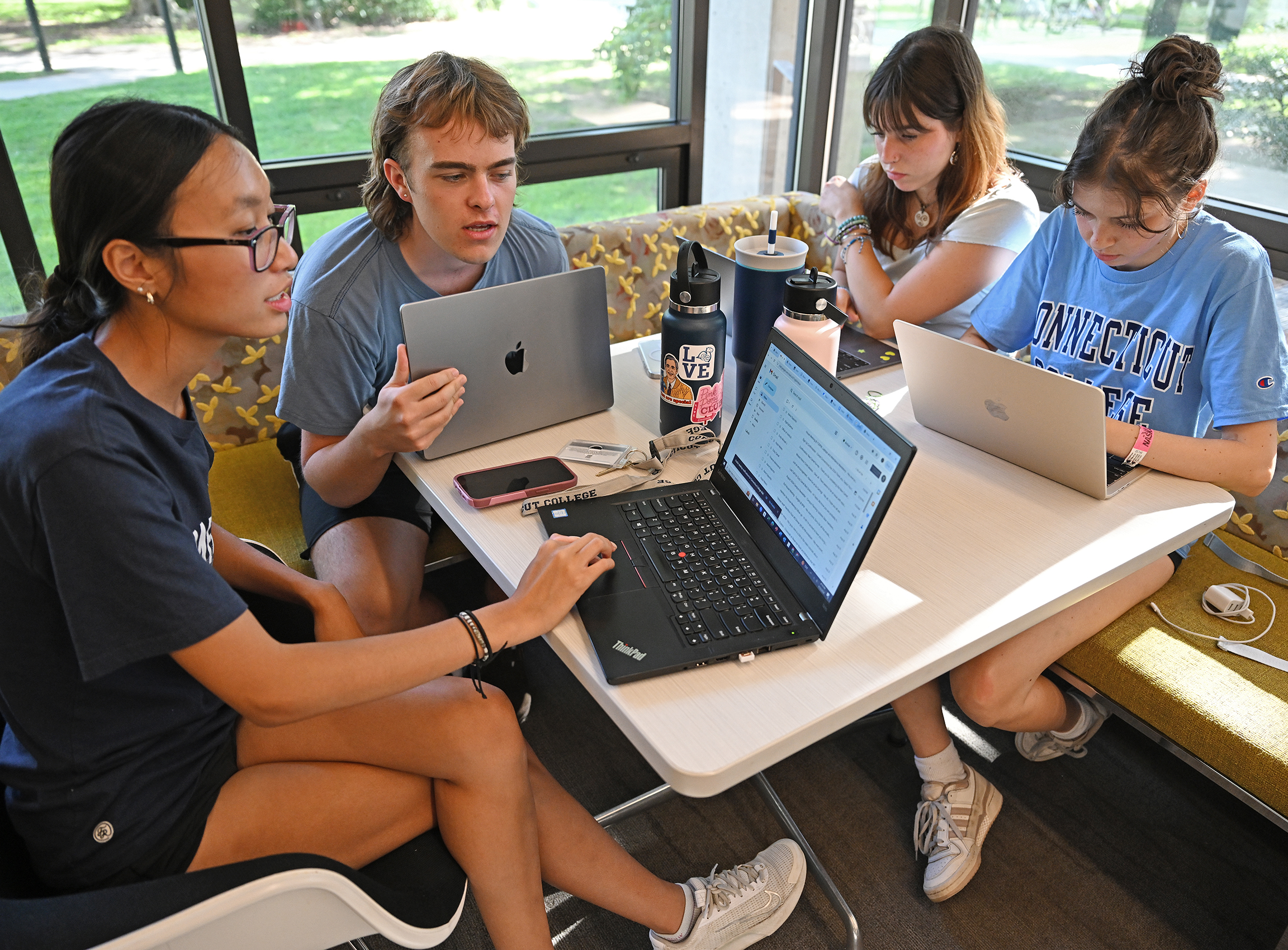 Four students gather around a table of laptop computers.