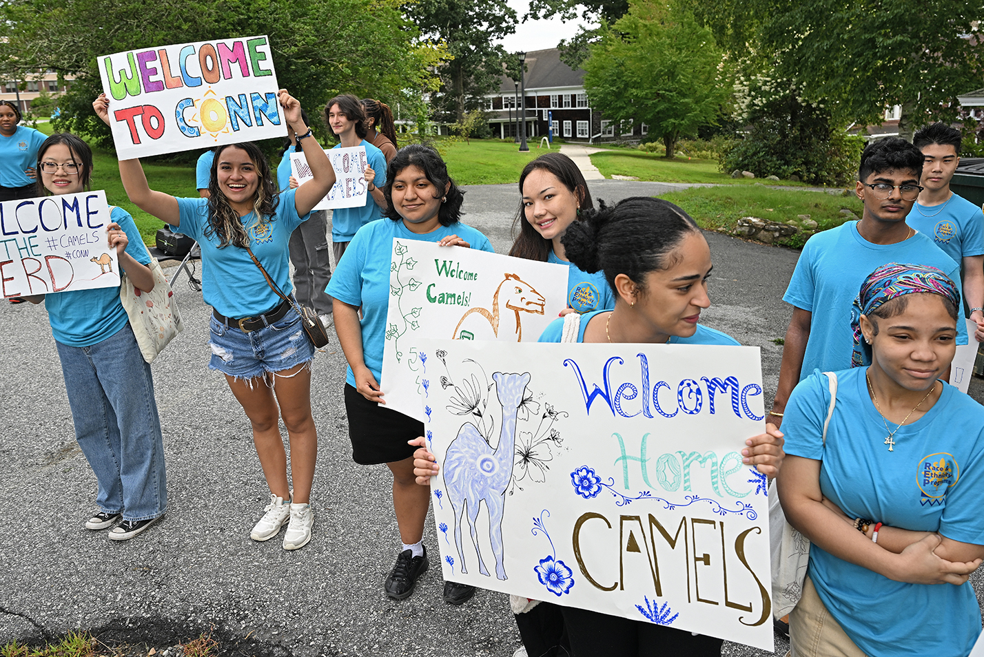 A group of students hold handmade welcome signs.