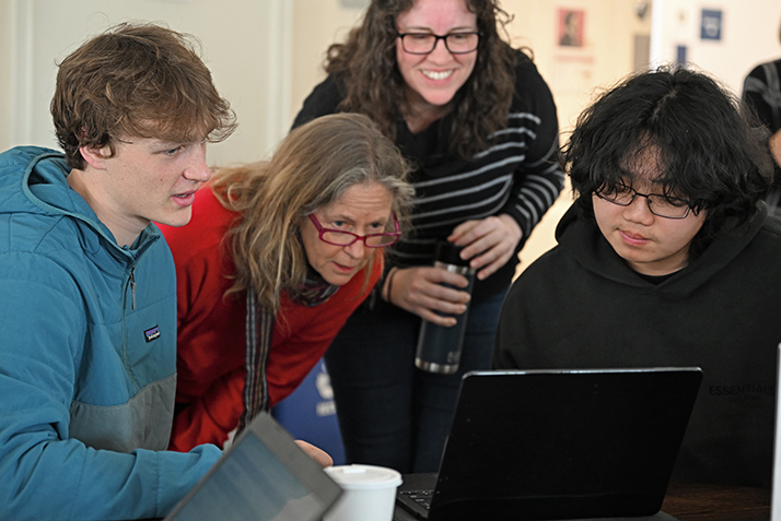 Students and staff gather around laptop computer
