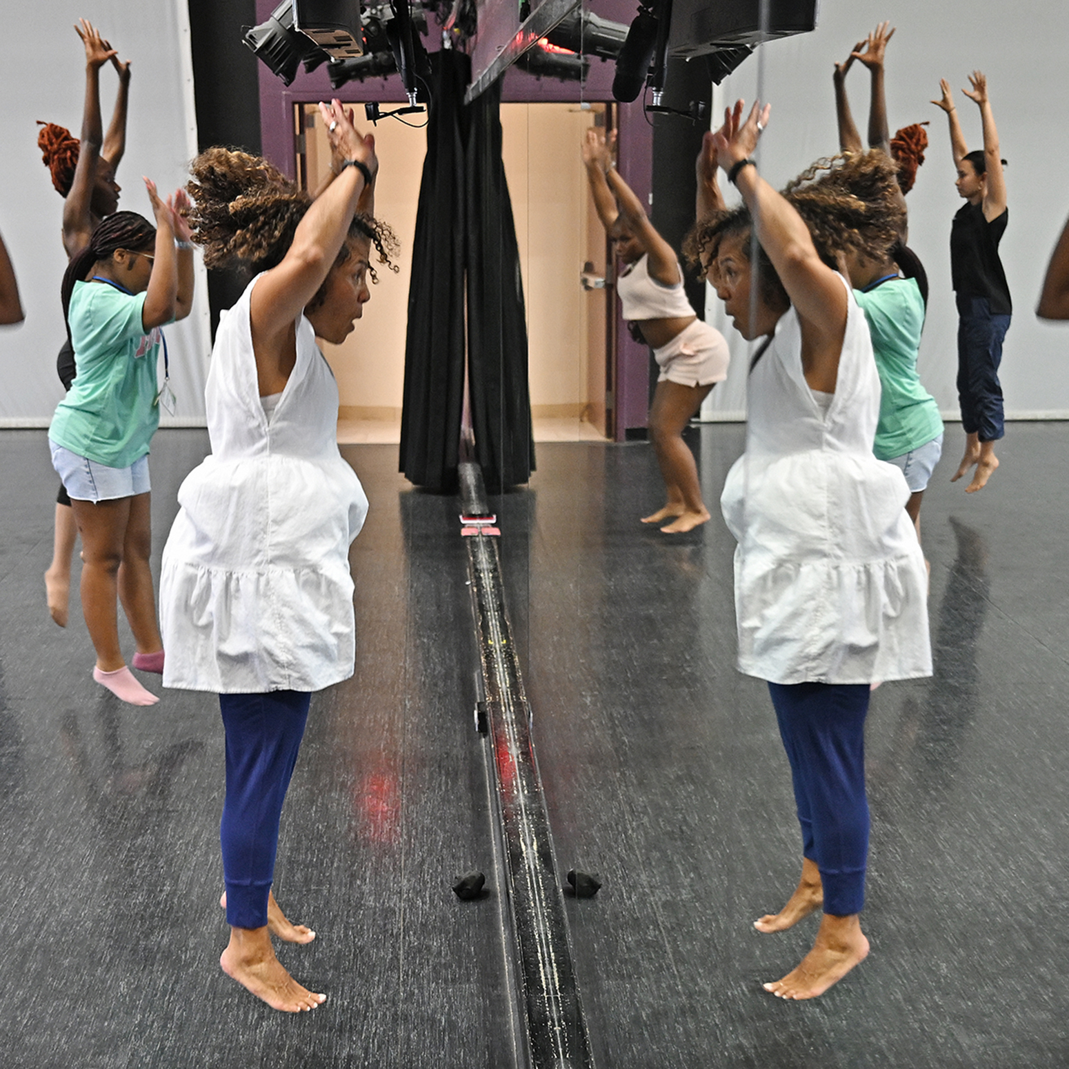 Dancers rehearse while reflected in a dance studio mirror