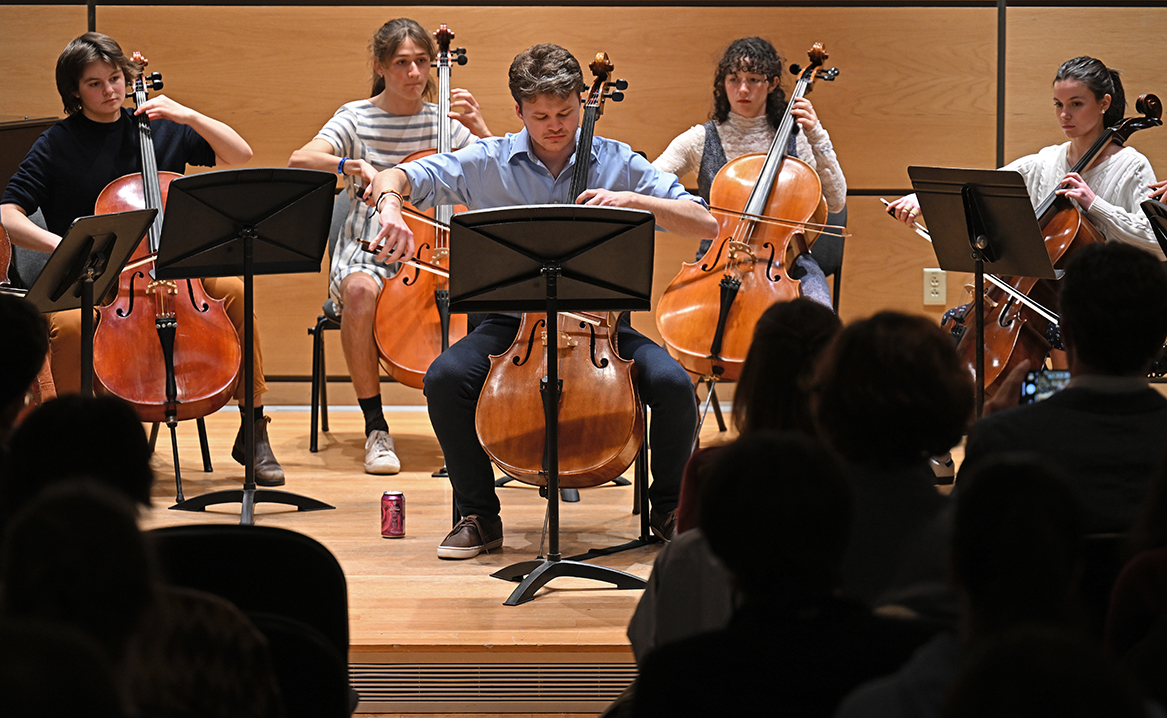 Student cello players perform on stage