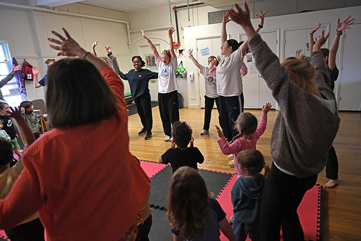 college students dance with preschoolers at a child care center