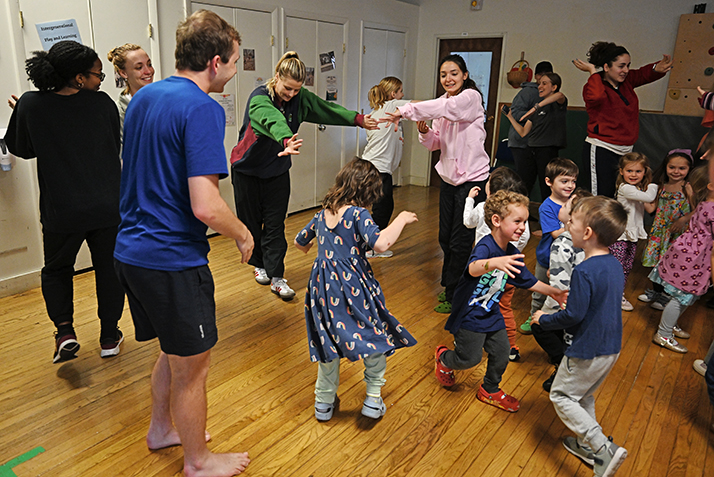 college students dance with preschoolers at a child care center