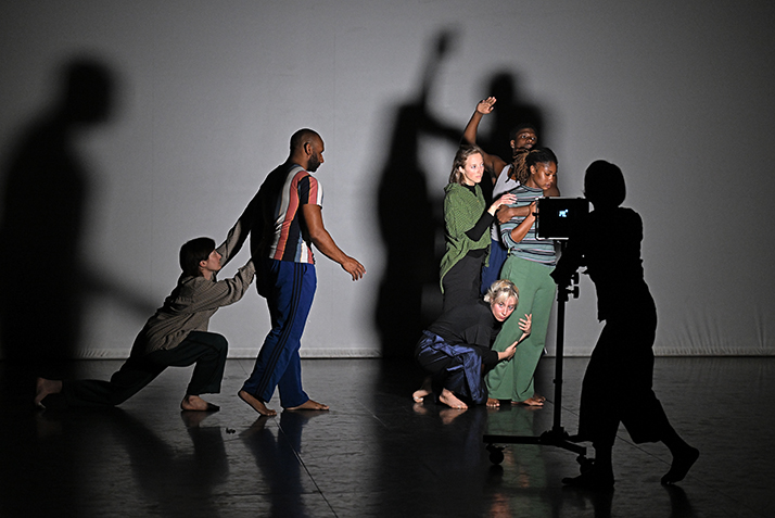 Modern dancers perform in dramatic lighting.