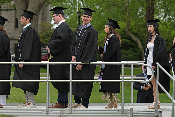 A line of students in caps and gowns wait to hear their names called during commencement expercises