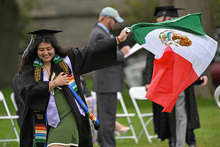 A graduate waves a Mexican flag as she crosses the stage to receive her diploma.