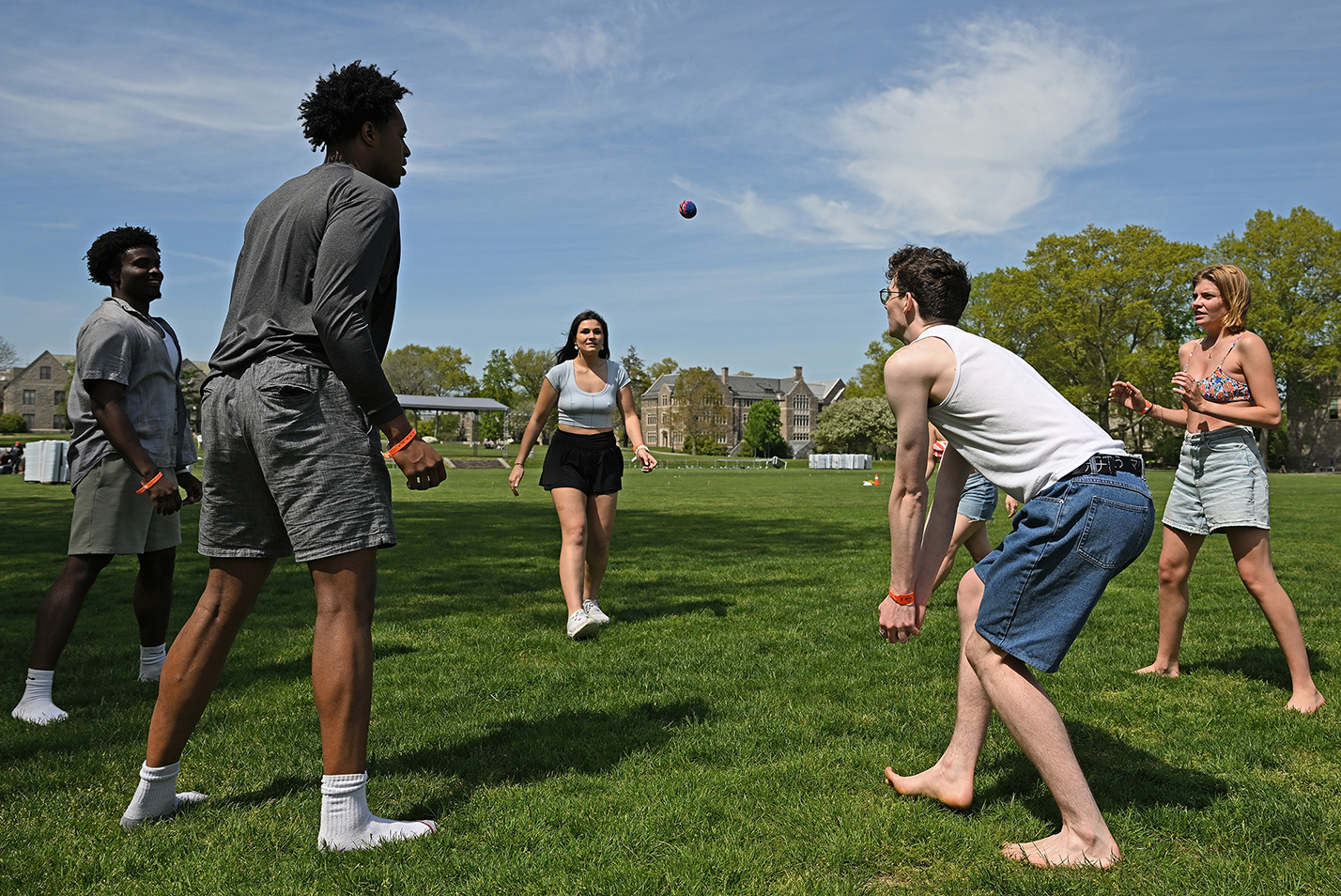 Students play hacky sack on a field.