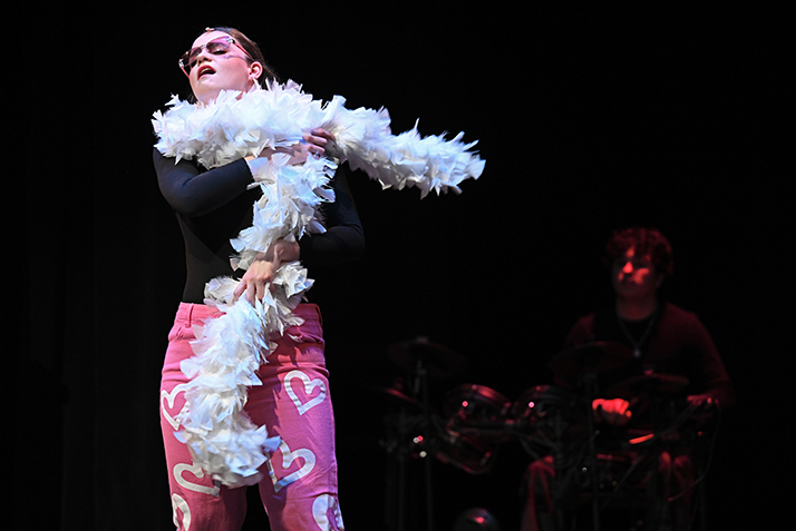 an actor dramatically dons a feather boa in a musical scene.