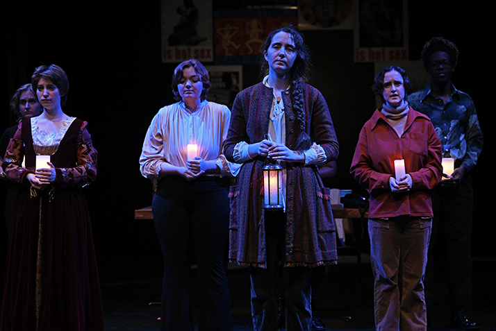 a group of actors hold lanterns in dim light on stage