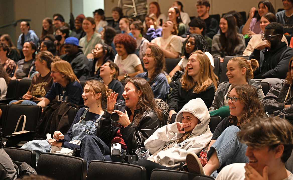 a crowd of students laugh at an improv performance