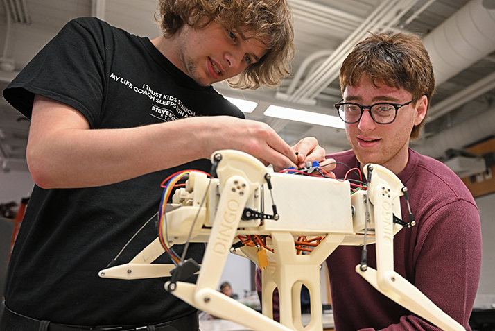 Two students work together on a four-legged robot.