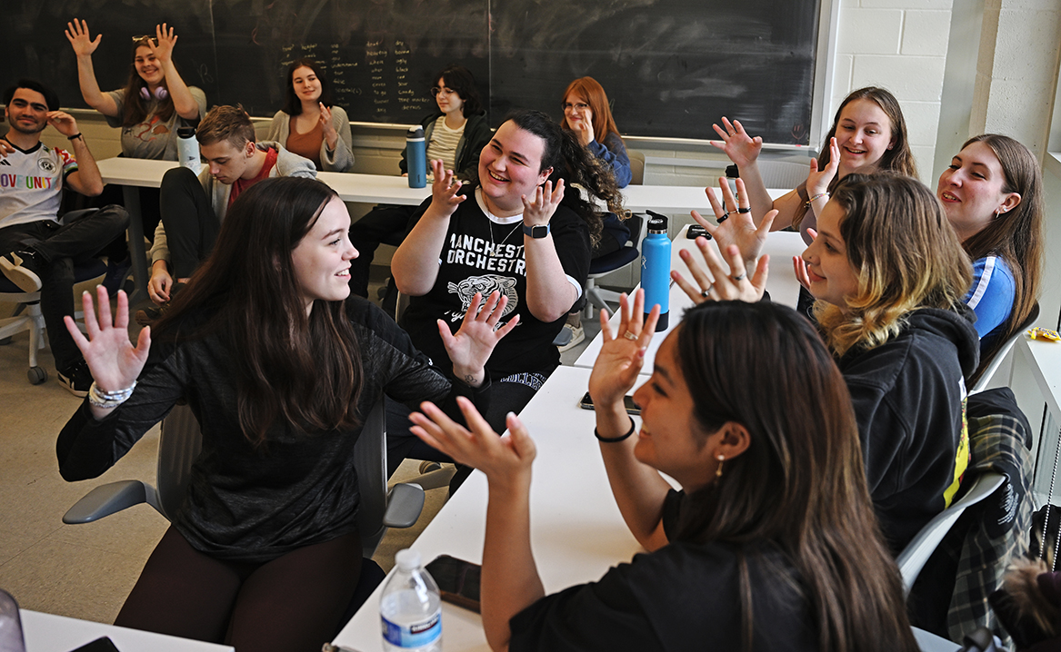 a group of students make a sign for applause in sign language class