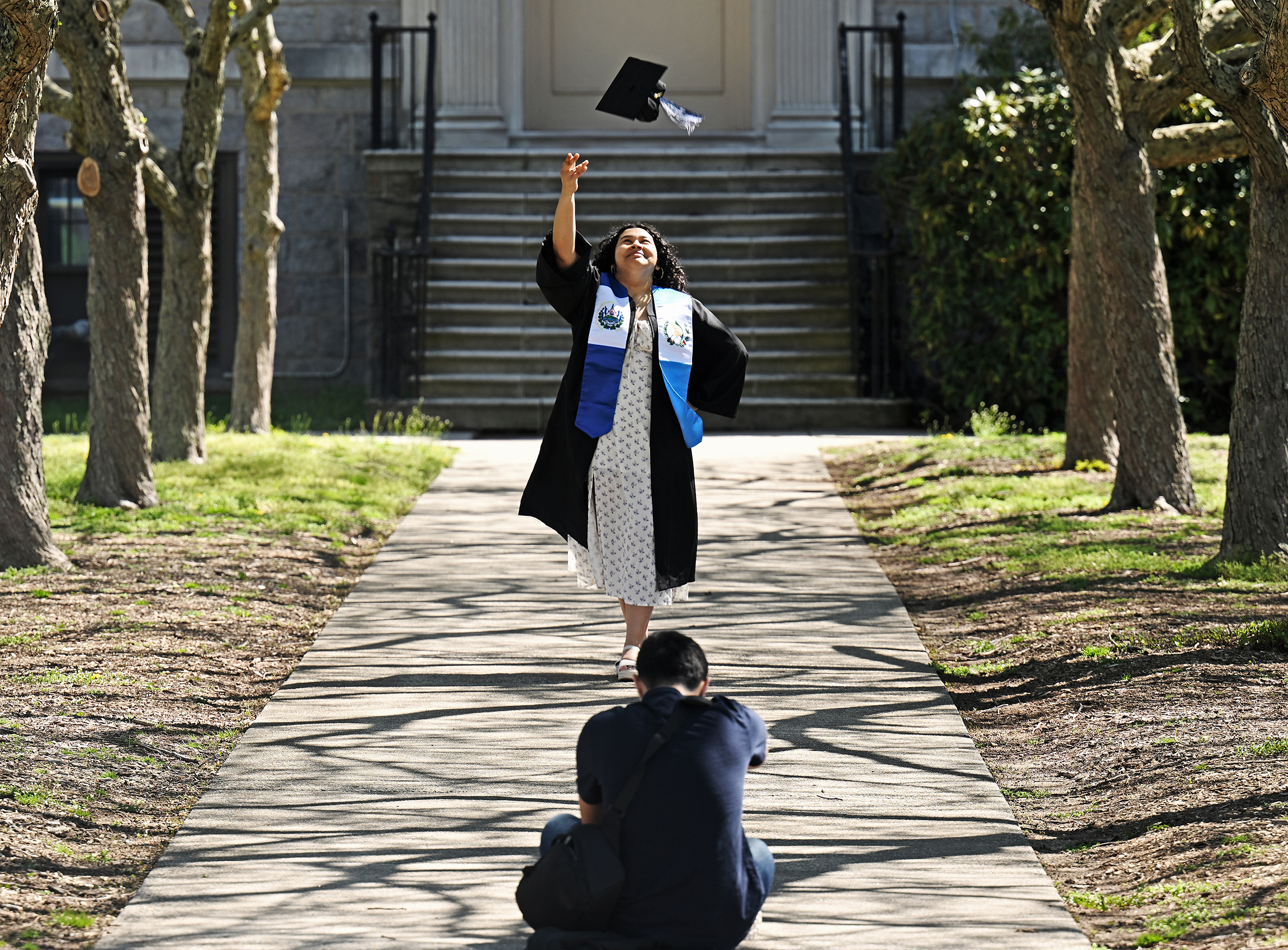 A student tosses a graduation cap in the air for a photo
