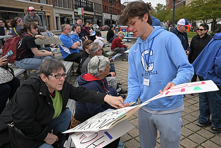 A student hands out posters at a community rally event