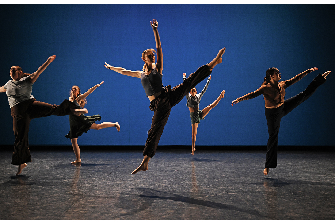 a group of dancer leap high in a graceful performance.