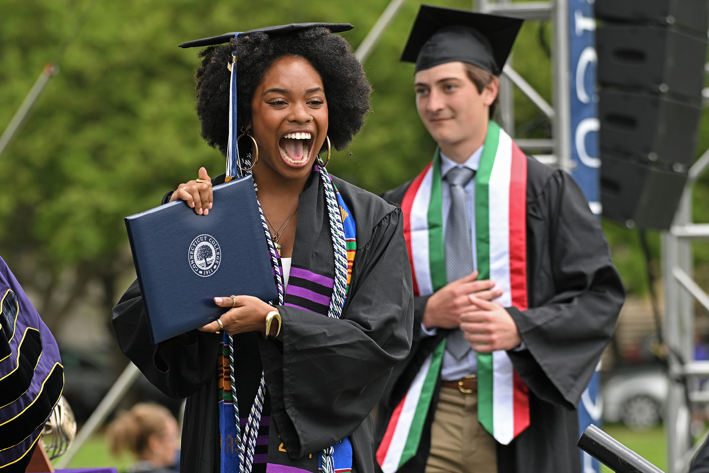 A student holds up a diploma after walking across the stage.