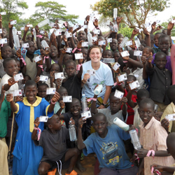 Brigid O'Gorman '11 poses with children from the Asayo's Wish Orphanage in Kaberamaido, Uganda. The children are showing off their new clinic cards.